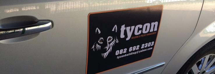 A car magnet advertising a building protection company on a beige car.
