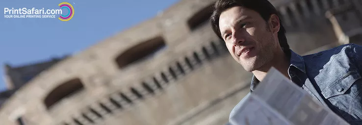A person standing outside with a travel brochure in his hands.