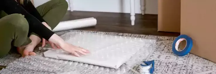 A woman securing an item in bubble wrap.