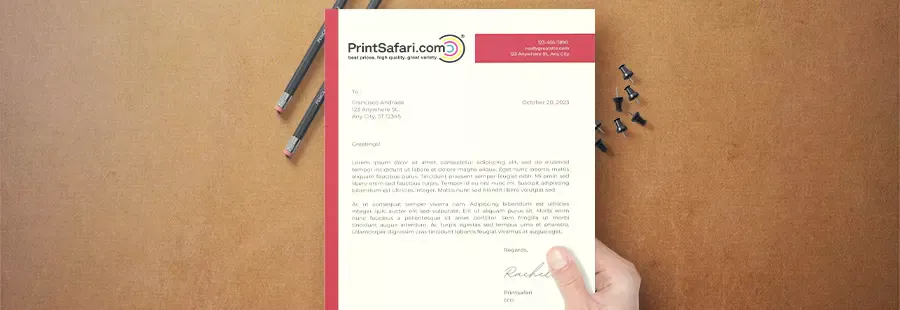 A red and white letterhead on top of a brown surface held by a hand.