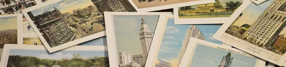 Several postcards of different sizes displayed on a table, featuring images of city buildings, churches, and other landmarks