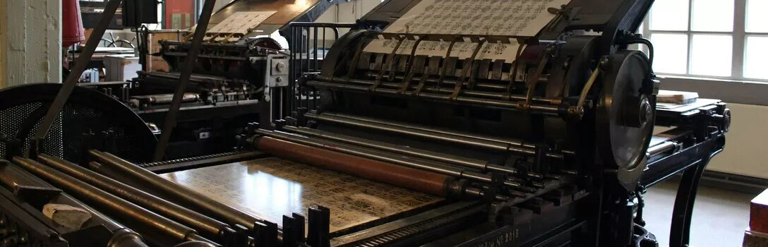 An antique, historical printing press on display in a museum, showcasing early printing technology.