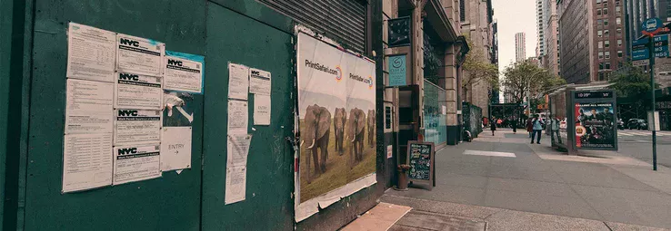 Posters on a wall next to a sidewalk