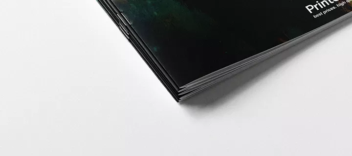 Close-up of four magazines stacked on top of each other, showing the saddle stitch binding and how it looks when stapled.