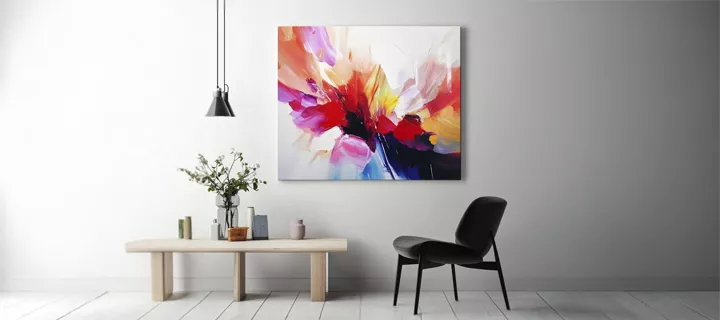 A colorful canvas print on a white wall, complemented by decor and a black chair in front.