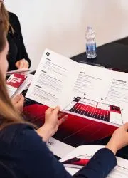 Professional reviewing a business brochure with marketing materials spread on desk