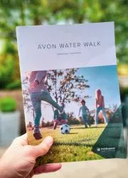 Hand holding vibrant real estate brochure showcasing community lifestyle photos