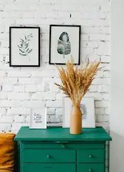 A dresser adorned with a vase, additional decor, and two framed pictures hanging on the wall, creating a cozy aesthetic.