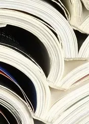 Close-up of several opened magazines stacked on top of each other, showcasing colorful pages and diverse layouts.
