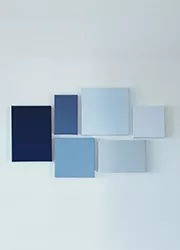 An arrangement of blue-toned canvases on a white wall, creating a geometric composition.