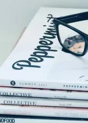Stack of printed lookbooks with stylish typography and glasses