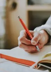 Student writing notes in an open textbook