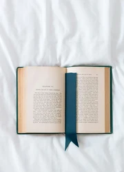 Book with a bookmark inside laying on a bed