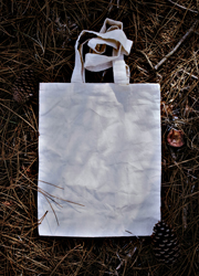 Stack of 100% natural white canvas tote bags, neatly folded, showing fabric texture and clean stitching details.