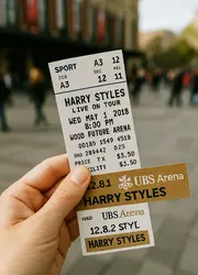 A hand holding a ticket outdoors.