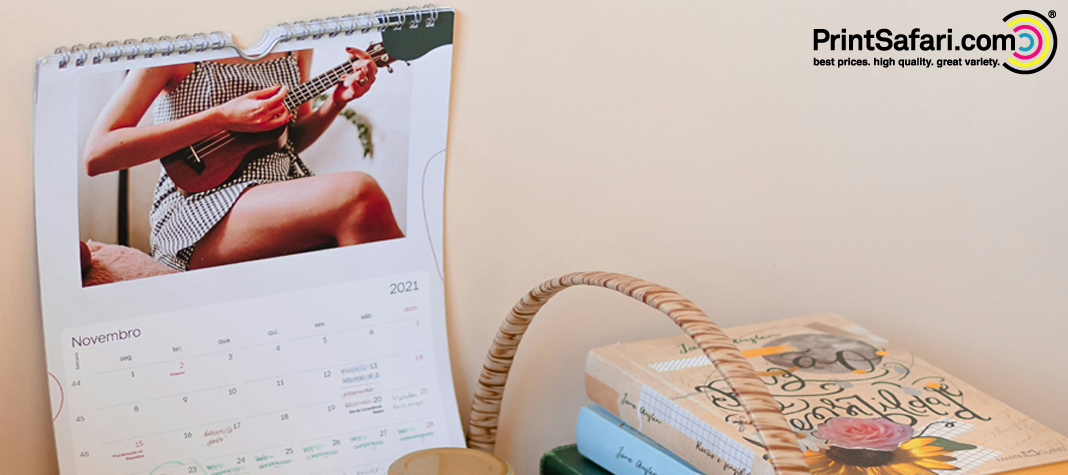 Desk calendar with spiral binding, open to a guitar-themed photo page, next to travel books.