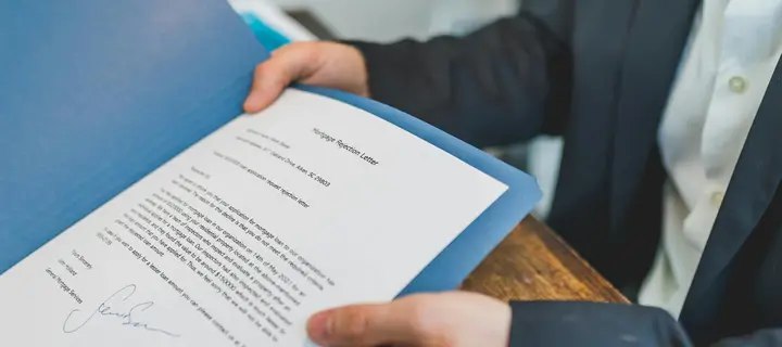 Hands presenting a document inside a blue presentation folder.