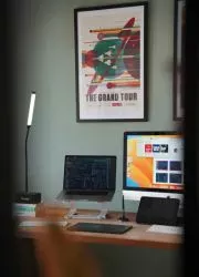 Stylish travel poster displayed above modern desk with computer setup