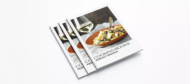 A cookbook featuring a table setting with white wine glasses and a delicious meal.