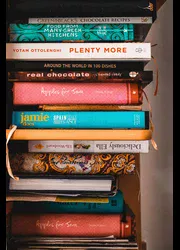 A stack of many different cookbooks.