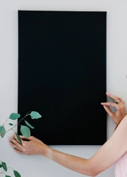 Person hanging up a black foam board poster