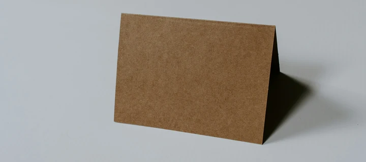 Folded business card made out of cardboard standing on a flat surface