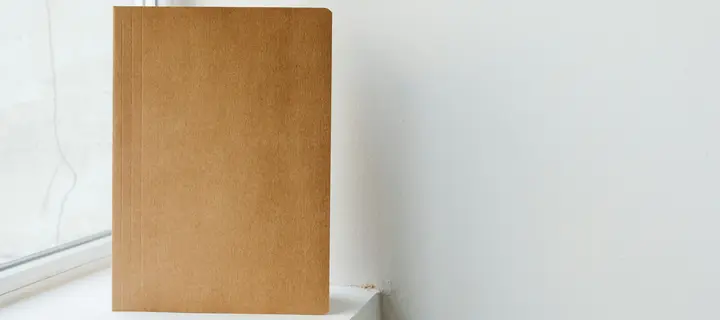 A brown presentation folder standing on a windowsill.