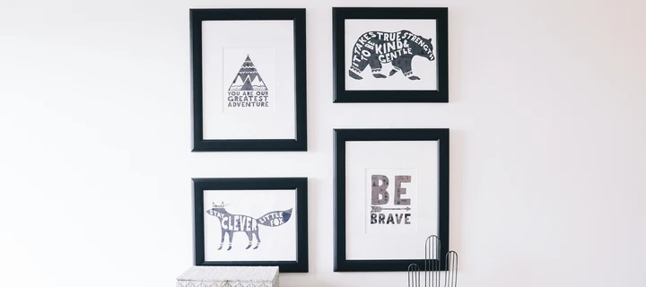 Four framed prints hanging in front of a white wall