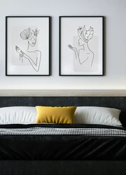 Two framed prints hanging on a wall over a bed