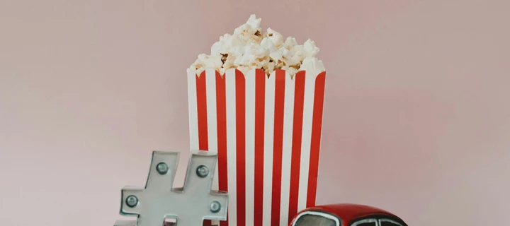 A red and white striped popcorn box filled with freshly popped popcorn
