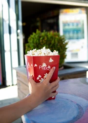 A hand holding a popcorn box on a table