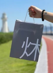 A hand holding a Paper Bag outside