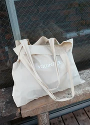 A full Canvas Bag laying on a bench