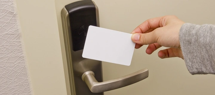 A white plastic key card being hold against a door.