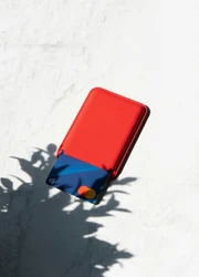 A blue plastic card inside a red wallet on a grey surface.
