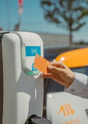 A hand holding an orange plastic card against a device.