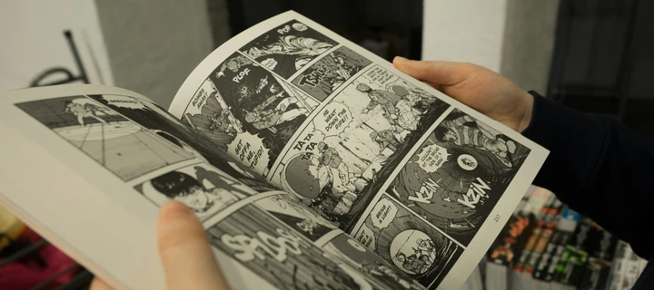 Close-up of a boy's hands holding a comic book, with only the book and hands visible.