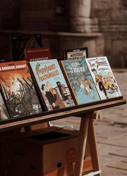 Several comic books arranged on an easel outdoors.