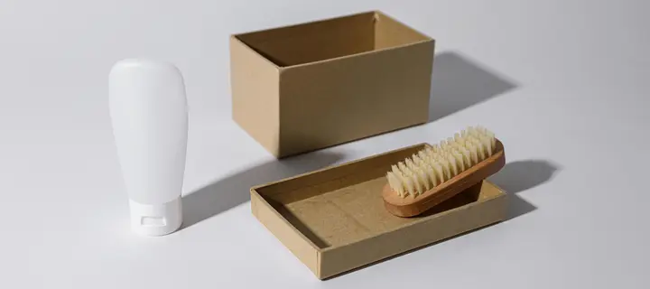An open cardboard box with a brush resting on its lid