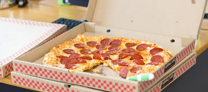 An open pizza box with the lid flipped up, revealing the inside