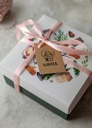 A cardboard box adorned with a ribbon and a small card attached