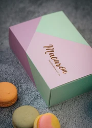 A paper box with macarons placed in front of it