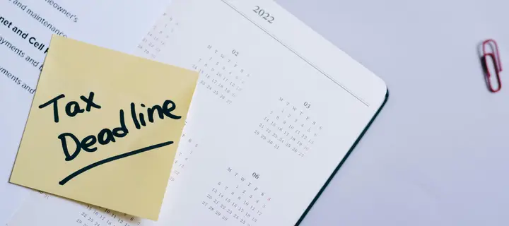 A year planner on a flat surface with a sticker reading 'Tax Deadline'.