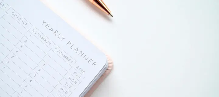 A year planner on a flat surface with a pen lying next to it.