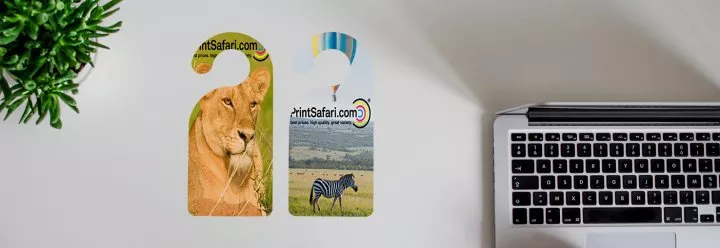 Two customized door hangers featuring safari-themed pet illustrations placed on a wooden desk.