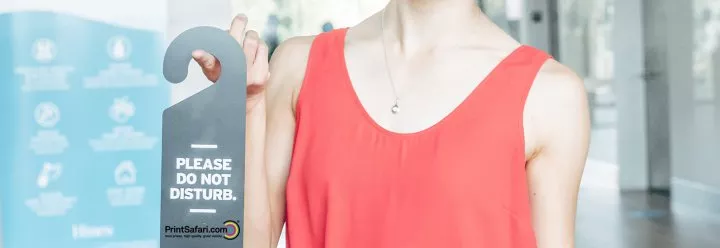 Woman in a red dress holding a door hanger on her finger.
