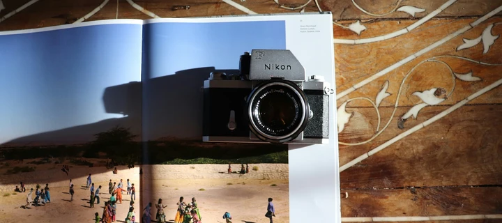 An open photography book with a camera laying on it