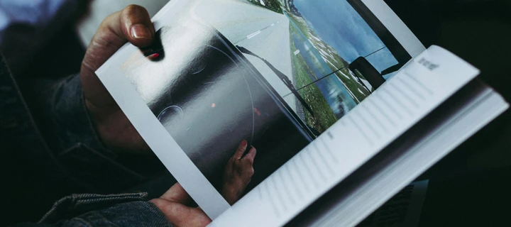 A photography book in the hands of a person who is currently looking at it