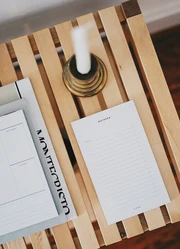 A notepad on a wooden dresser with a candle placed on it