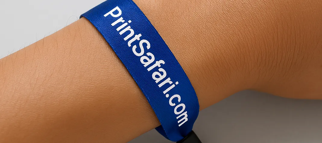 A blue Tyvek wristband with the PrintSafari.com logo and tagline worn on a wrist
